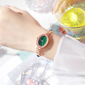 Elegant rose gold women's watch with green oval dial and diamond markers on a wrist