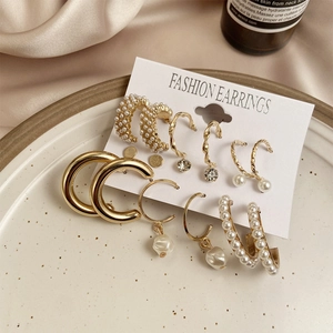 Detail of vintage 9-piece gold earring set with pearls and crystals on silk background