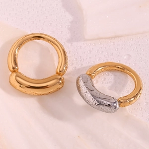 Macro detail of gold and silver chunky rings with water droplets on a white textured surface