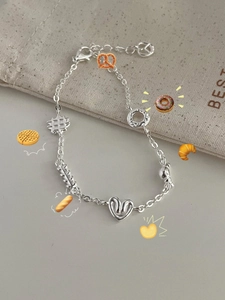 Detail of S925 sterling silver bracelet with donut and croissant pastry charms