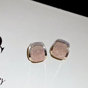 Macro shot of 18k gold plated square stud earrings with pink glitter finish