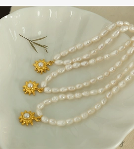 Detailed close-up of French style pearl necklace with a gold sun pendant on a shell tray