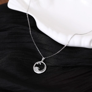 Macro detail of silver ocean wave pendant on shell with black background