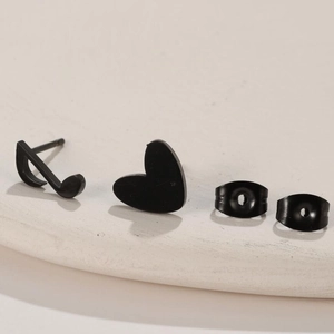 Close-up of matte black stainless steel asymmetric earrings with music note and heart shapes