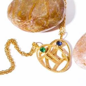 Macro detail of gold Gemini zodiac necklace with blue and green turquoise stones