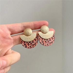 Detail of round geometric leopard print earrings with brushed gold metallic finish