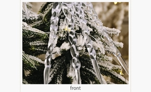 Macro shot of clear twisted icicle ornaments hanging on a snowy Christmas tree branch