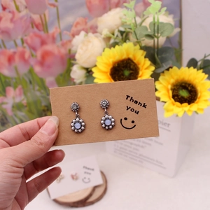 Floral earrings with blue beads and white pearls on a thank you smile paper card