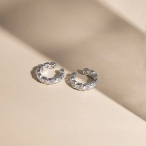 Detail shot of silver ear cuffs with sparkling white cubic zirconia stones on textured base