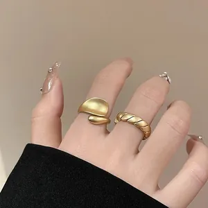 Detailed close-up of matte gold bean ring and twisted rope band worn on hand