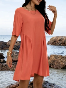 Detail of coral orange pleated dress showing waist stitching and loose A-line silhouette