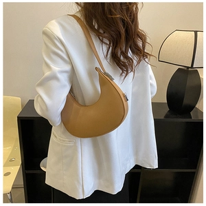 Detail view of a khaki leather hobo bag with adjustable silver buckle on a white blazer