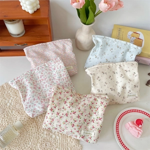 Flat lay of five floral cotton makeup bags in various colors on a white desktop