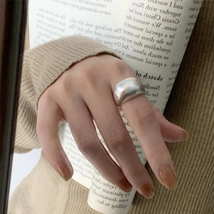 Minimalist wide matte 925 silver ring shown on a hand with a newspaper background