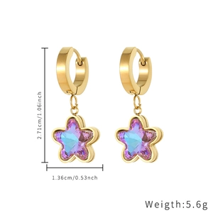 Detailed view of gold huggie earrings featuring star pendants and blue crystals