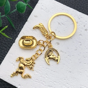 Macro detail of western cowboy boot and hat charms on a vintage gold metal keychain