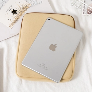 Detail of beige felt tablet sleeve with brown trim on a minimalist white desk setup