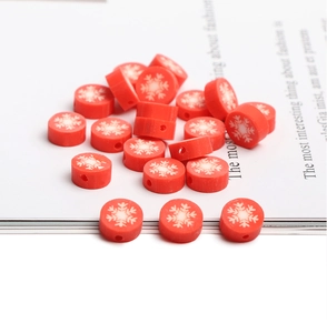 Macro shot of red polymer clay beads with white snowflake patterns for DIY jewelry