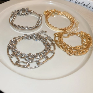 Detail of multi-layered metal chain bracelets and O-ring bangles in gold and silver