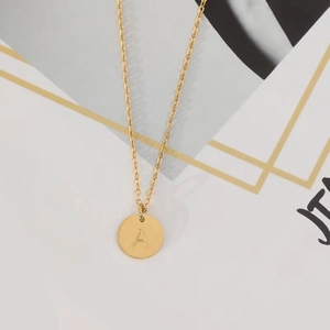 Detail shot of a round gold pendant featuring an engraved letter A on a sleek O-chain link