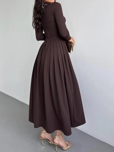 Détail d'une robe longue plissée marron foncé à manches longues avec une coupe trapèze fluide
