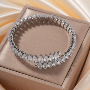 Close-up of silver rhombic bangle with marquise-cut zircon stones on silk background