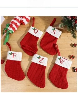 Close-up of red knitted Christmas stockings with white cuffs and festive letter embroidery