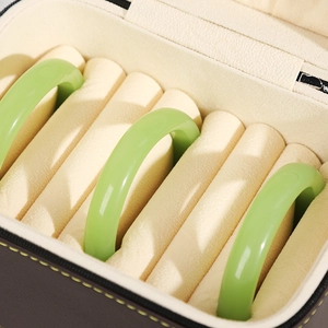 Brown PU leather bracelet storage box with beige velvet interior and three green bangles