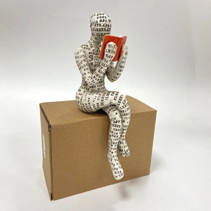 Close-up of a reading woman sculpture with black letters and a bright orange book