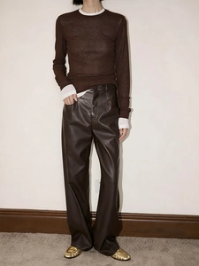 Detail of brown semi-transparent textured knit top paired with stylish PU leather trousers