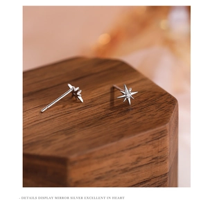 Macro shot of silver eight-pointed star earrings with zircon on a wooden stand