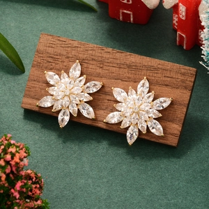 Luxurious gold snowflake earrings with marquise zircon stones on festive holiday background