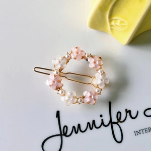 Detail of pink floral hair clip with pearl center and golden metal base structure