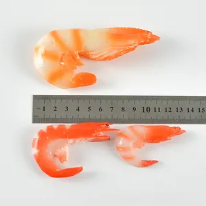 Detailed view of three different sized realistic resin shrimp keychains with a ruler for scale