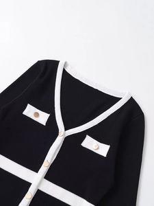Detail of V-neck cardigan featuring white contrast piping and gold metal buttons