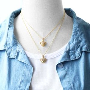 Detail of gold double-layered necklaces featuring sparkling crystal bear head pendants