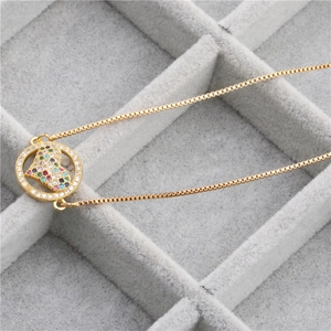 Macro detail of gold snake chain necklace featuring a colorful heart crystal pendant