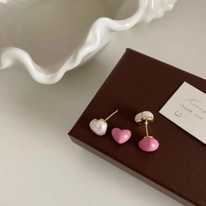 Elegant heart-shaped pearl earrings in pink and cream on a decorative gift box