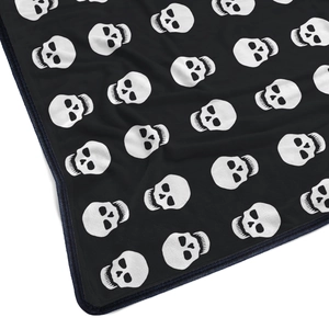 Close-up of flannel blanket with white skull patterns and durable stitched edges