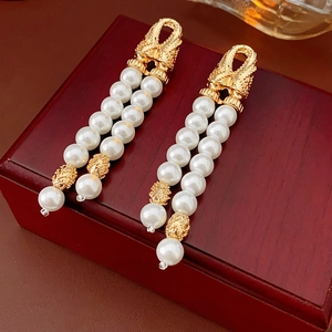 Detailed close-up of double-layer faux pearl drop earrings with golden metal accents