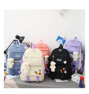 Close-up of five macaron-colored canvas backpacks with cute bear charms and badges
