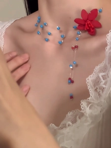 Nahaufnahme einer handgefertigten Perlenkette mit roter Blume am Hals getragen