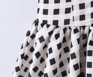 Macro shot of black and white plaid dress with satin texture and pleated waist detail