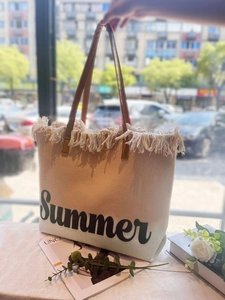 Detail der beigen gewebten Strandtasche mit braunen Trägern und Summer-Stickerei