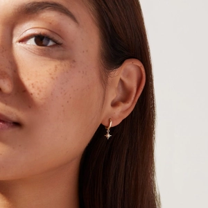Gros plan d'une boucle d'oreille créole dorée avec pendentif étoile sur oreille