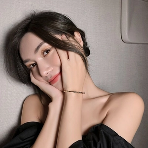 Detail of a minimalist gold bamboo joint open bangle on a female model's wrist