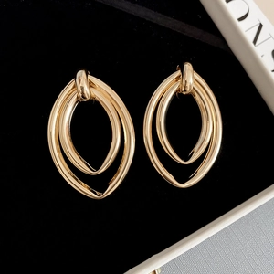 Gros plan détaillé de boucles d'oreilles ovales doubles dorées sur velours noir