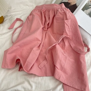 Detailed view of pink cotton apron featuring large front pockets and drawstring waist tie