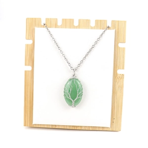 Silver Tree of Life necklace with oval green crystal stone on wooden display