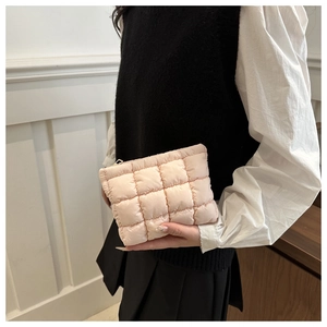 Close-up of a model holding a soft quilted light pink nylon down-padded clutch bag